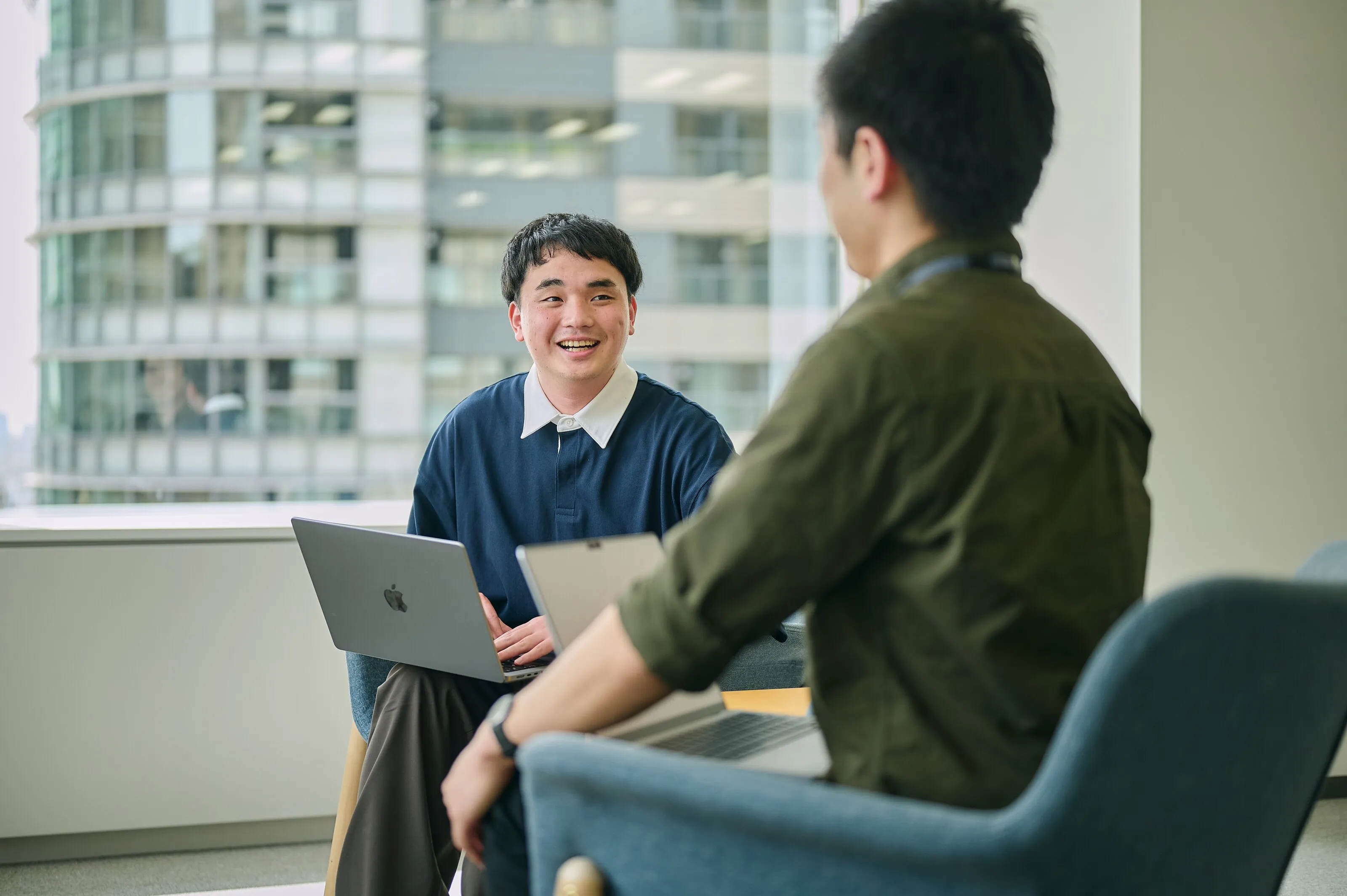 ノートPCを手元に置き、笑顔で話す二人のエンジニア